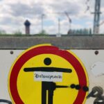 Foto mit industrieller Landschaft im Hintergrund und einem Schild im Vordergrund